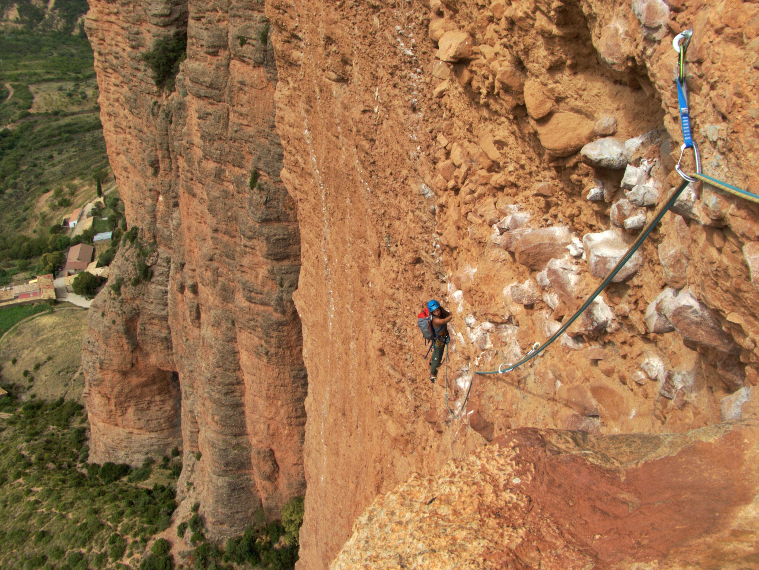 Cliente escalando una vía de varios largos en Riglos con el paisaje de los Pirineos al fondo.