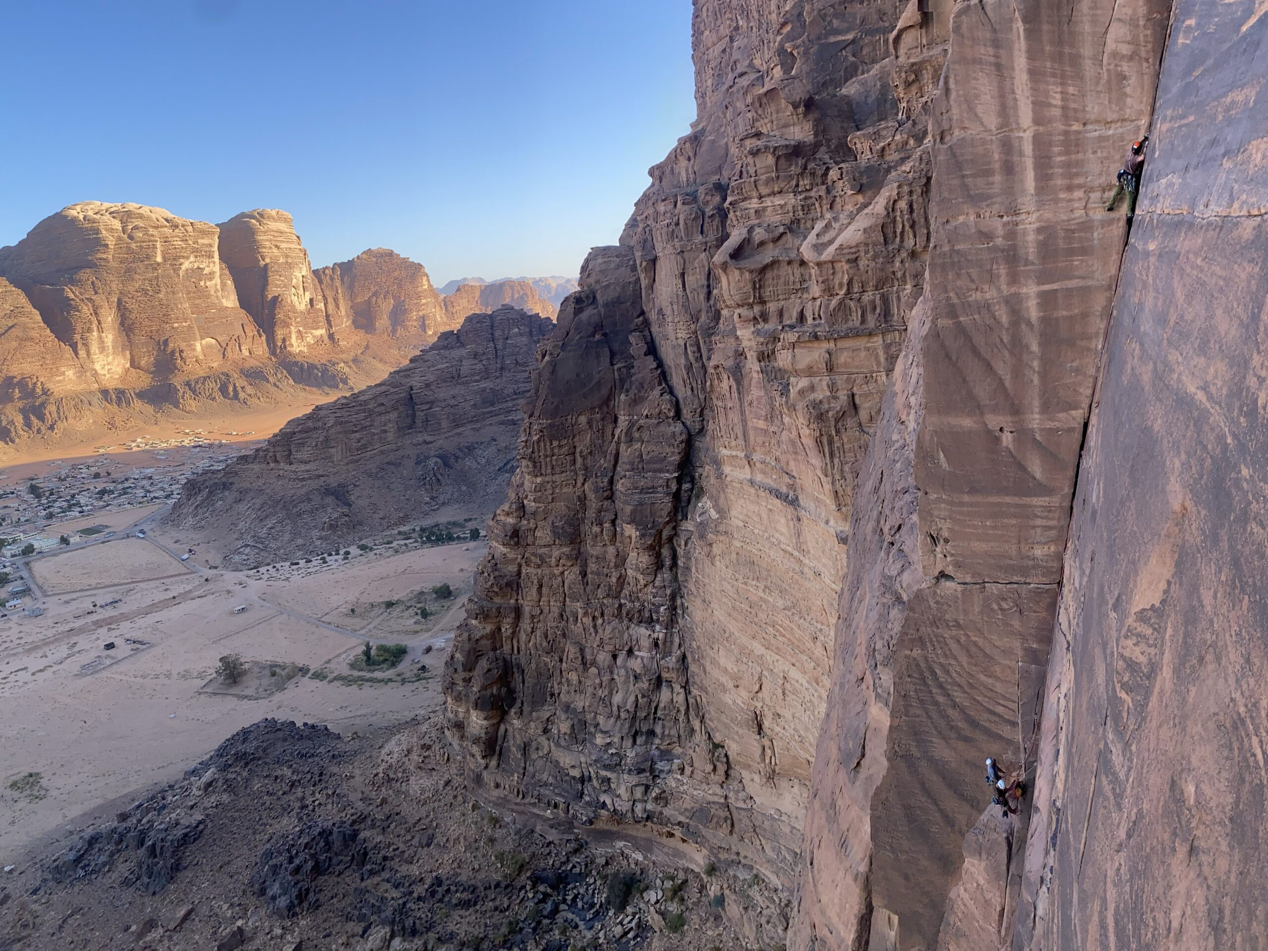 Escalador ascendiendo una pared de arenisca en Wadi Rum, Jordania, durante una actividad guiada de varios largos.